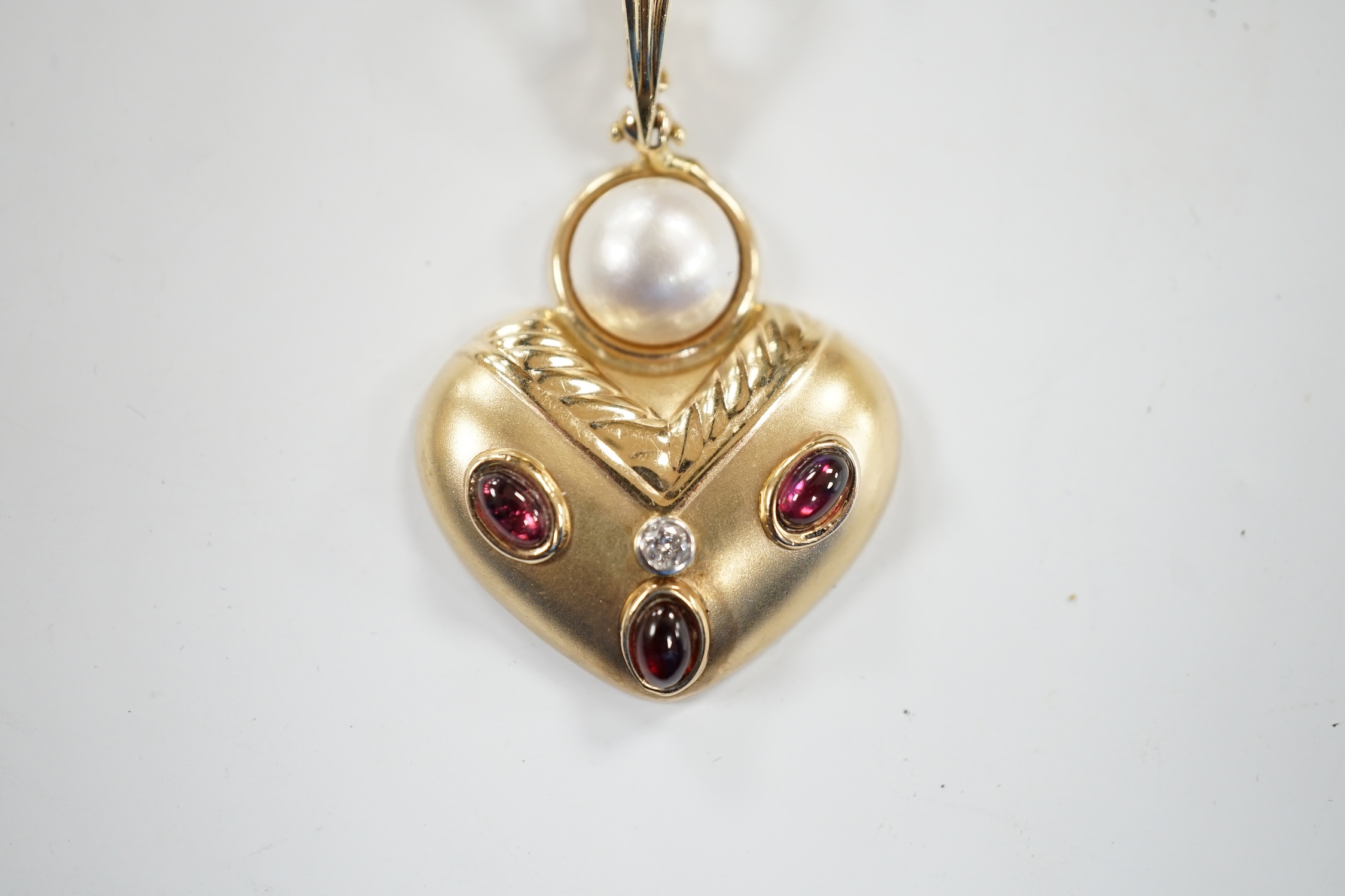 A modern unmarked yellow metal, mabe pearl, cabochon garnet and diamond set pendant, width 28mm, gross weight 5.6 grams.